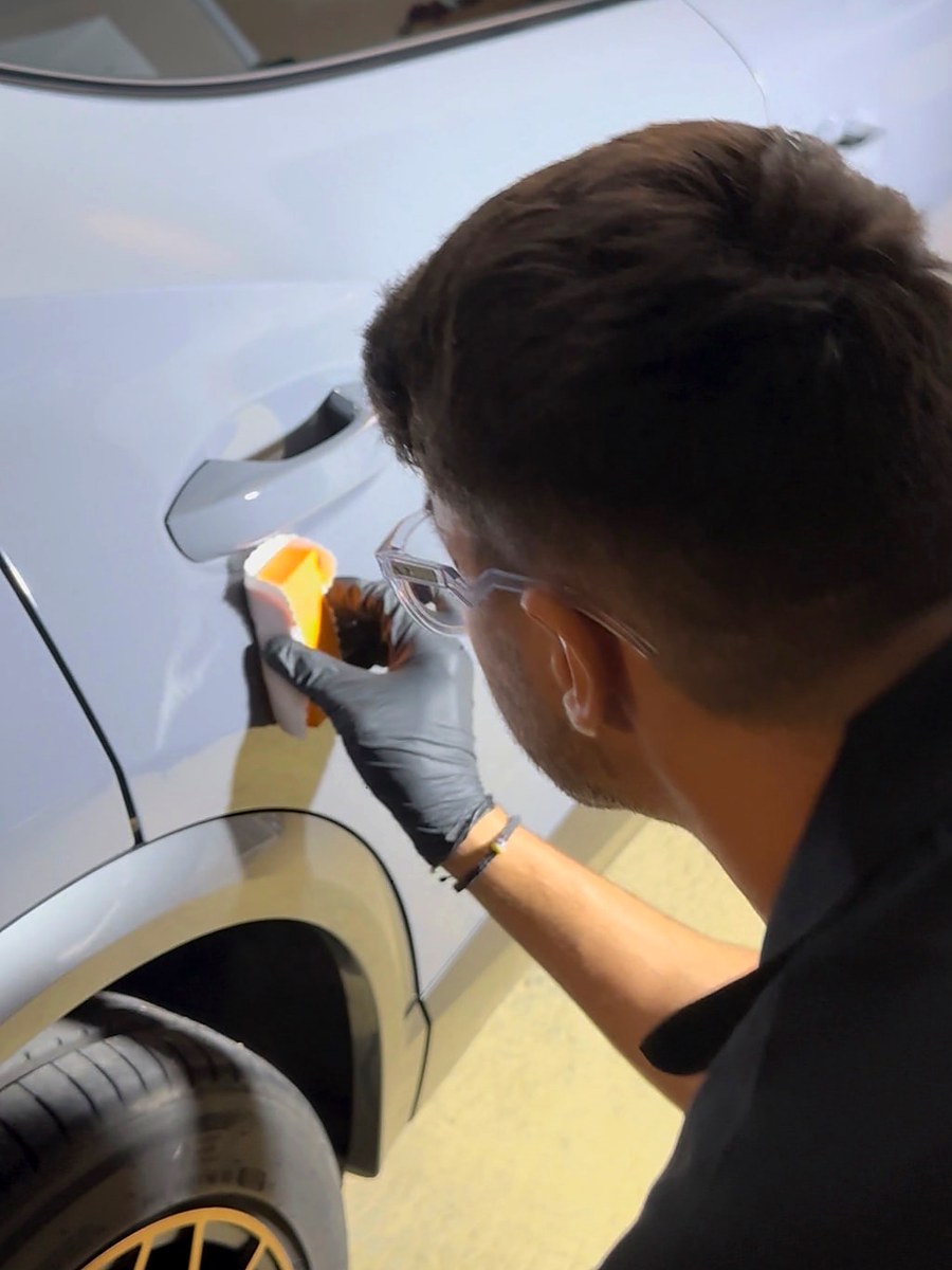 Application d’une protection au bloc applicateur sur une carrosserie gris clair — photographie réelle